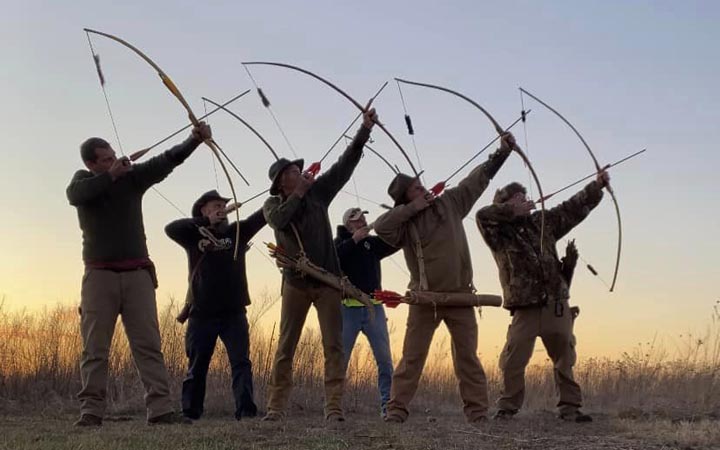 Archery students draw their bows at sunset.